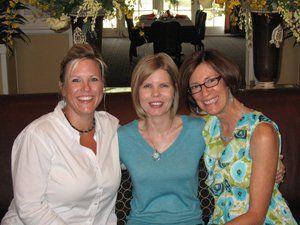 Three women are posing for a picture together and smiling