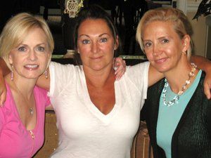 Three women are posing for a picture with their arms around each other.