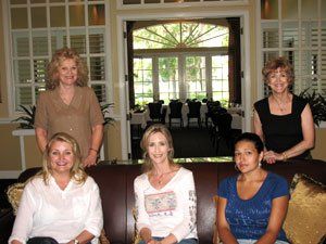 A group of women are posing for a picture while sitting on a couch