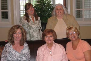 A group of women are posing for a picture while sitting on a couch.