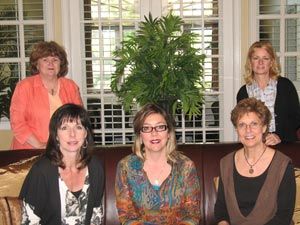 A group of women are posing for a picture while sitting on a couch.
