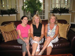 Three women are posing for a picture while sitting on a couch