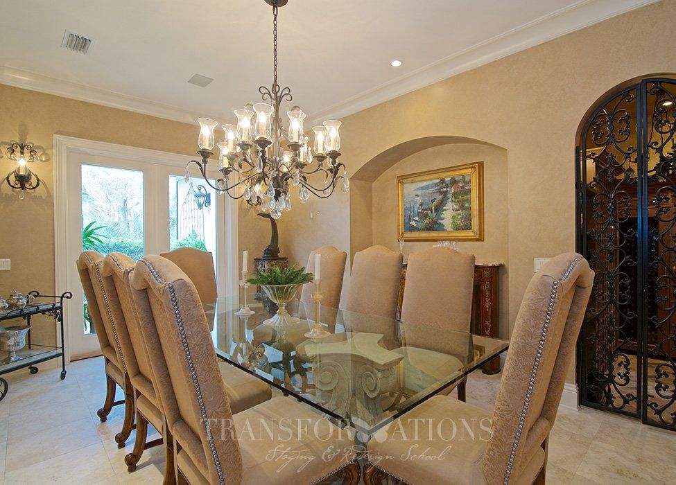 A dining room with a glass table and chairs and a chandelier