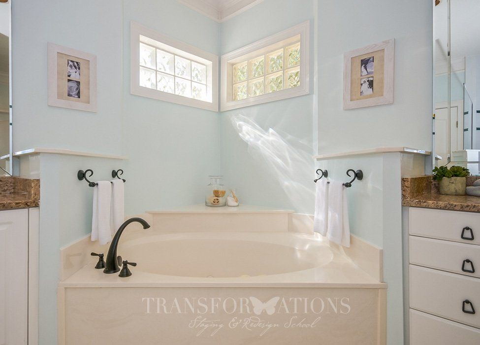 A bathroom with a tub , sink , mirror and window.