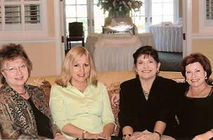 A group of women are posing for a picture while sitting on a couch.