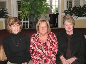 Three women are posing for a picture while sitting on a couch