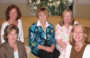 A group of women are posing for a picture while sitting on a couch.