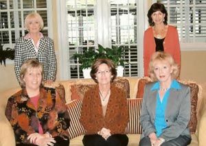 A group of women are posing for a picture while sitting on a couch