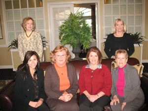 A group of women are posing for a picture while sitting on a couch