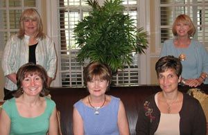 A group of women are posing for a picture while sitting on a couch