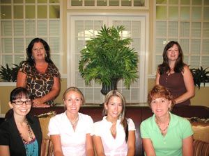 A group of women are posing for a picture in front of a plant