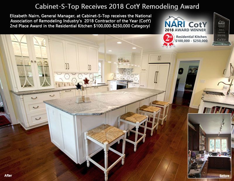 A kitchen with white cabinets and a large island with stools.
