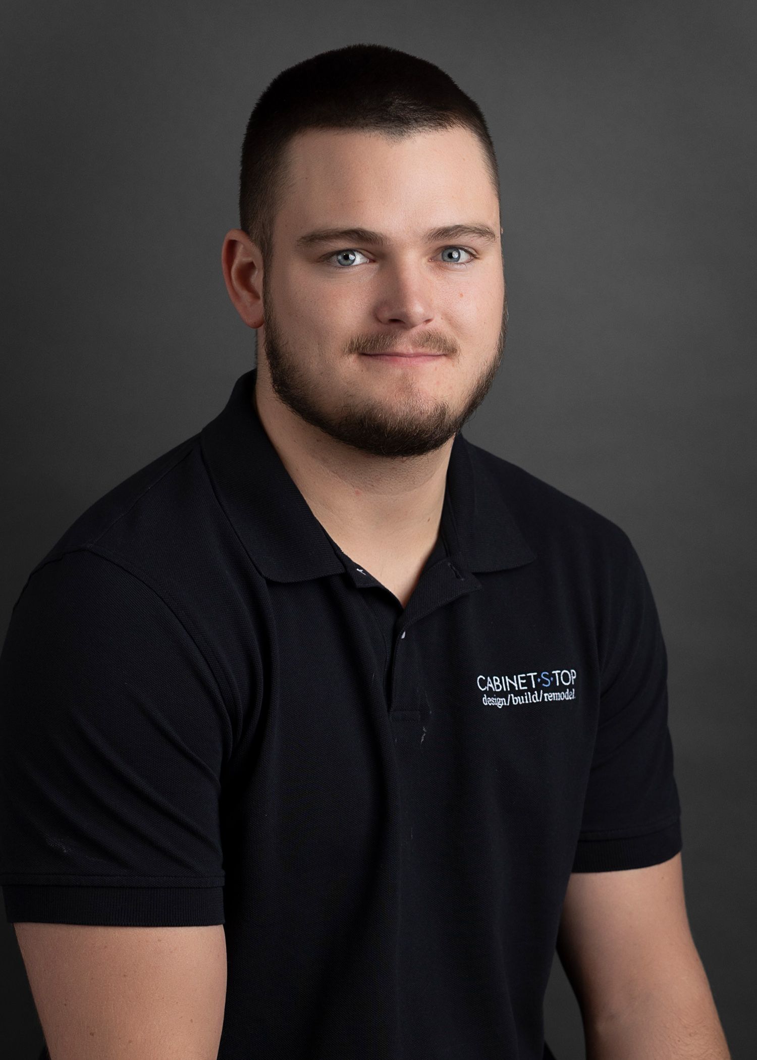 A young man wearing a black shirt is smiling for the camera.