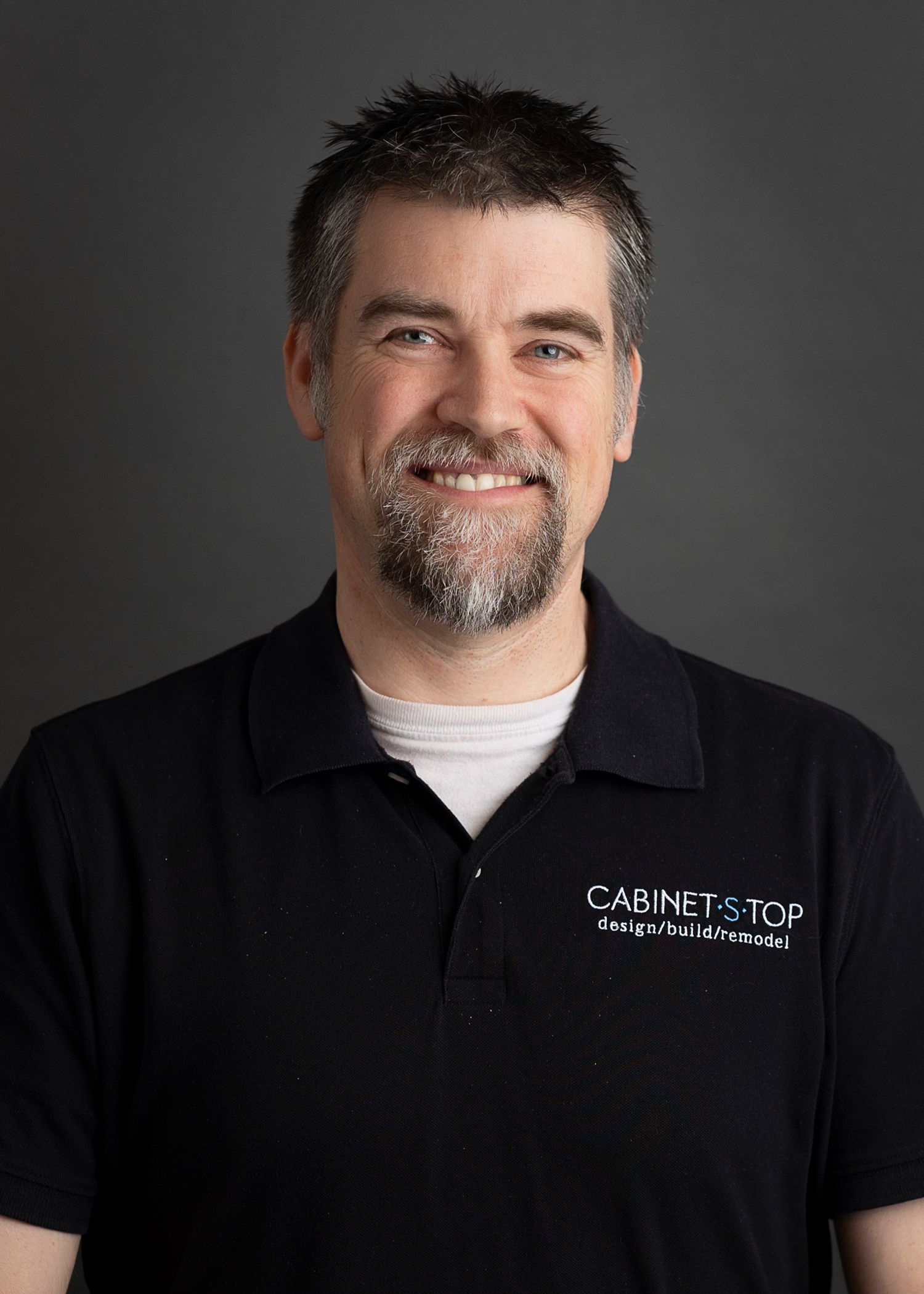 A man with a beard is smiling and wearing a black shirt
