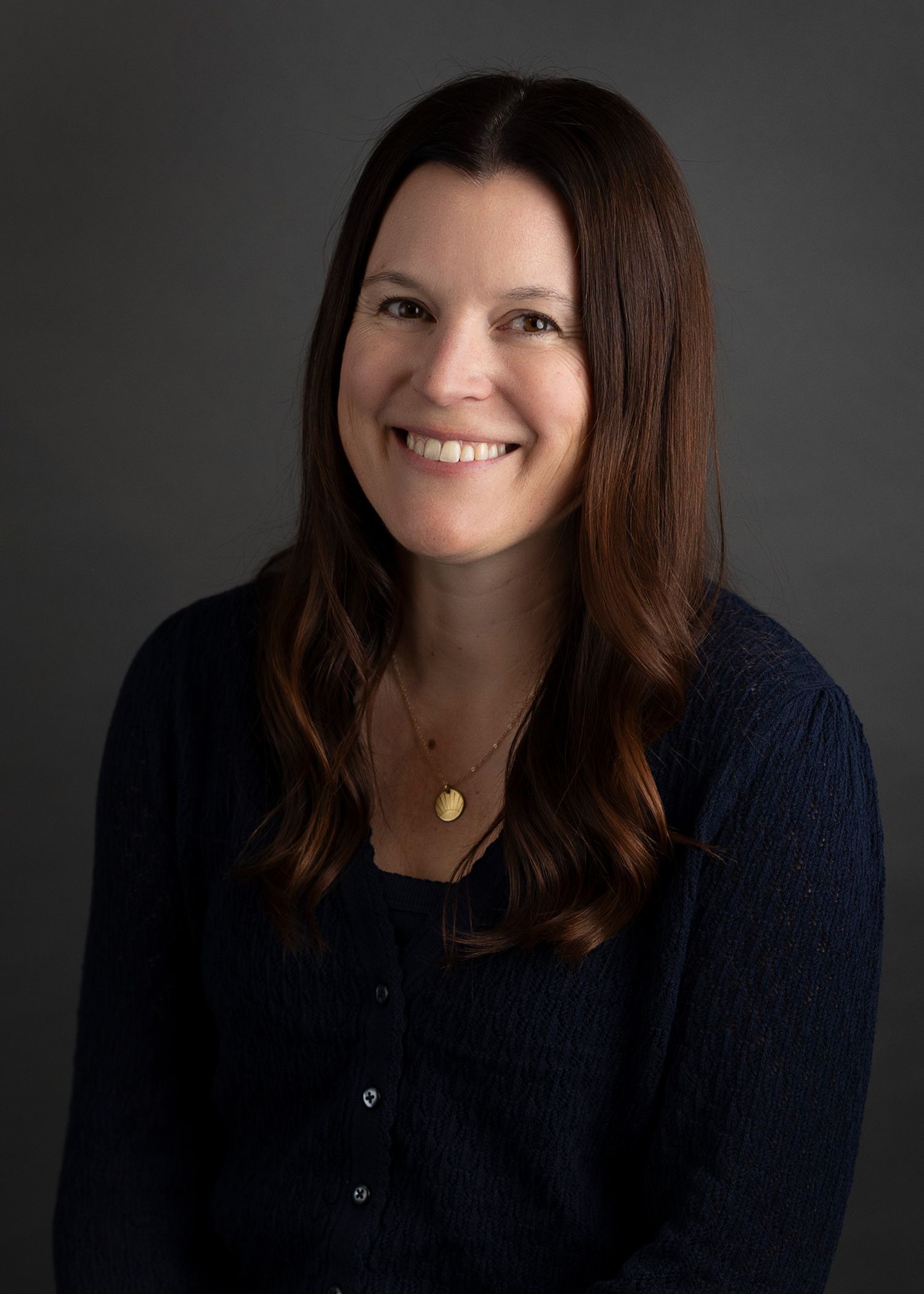 A woman in a red sweater is smiling for the camera.