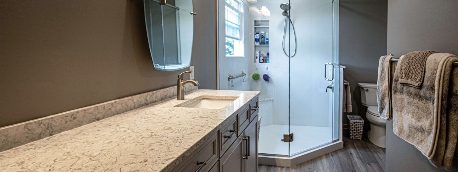 A bathroom with a sink , toilet , shower and mirror.