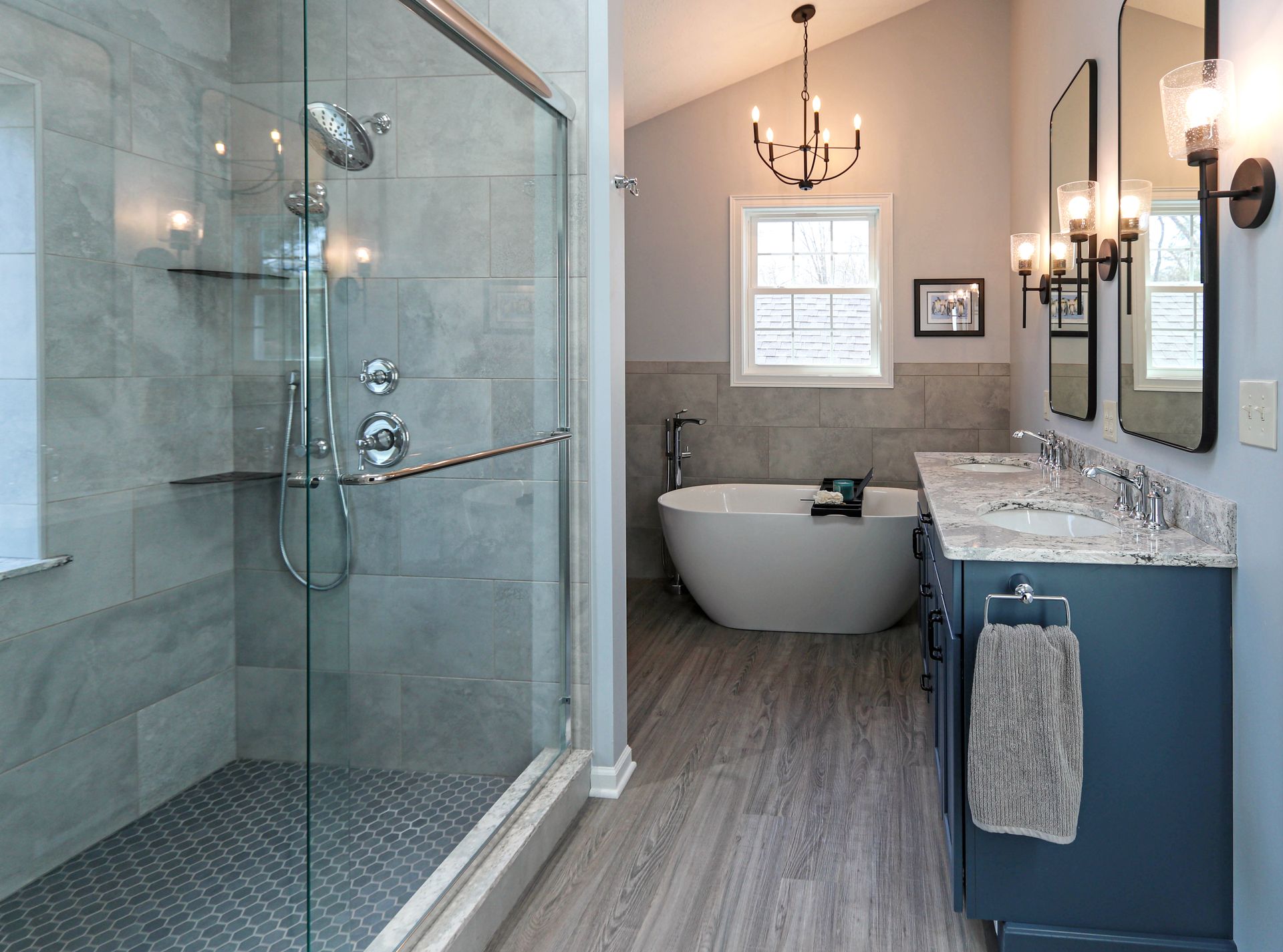 A bathroom with a tub , sinks , and a walk in shower.