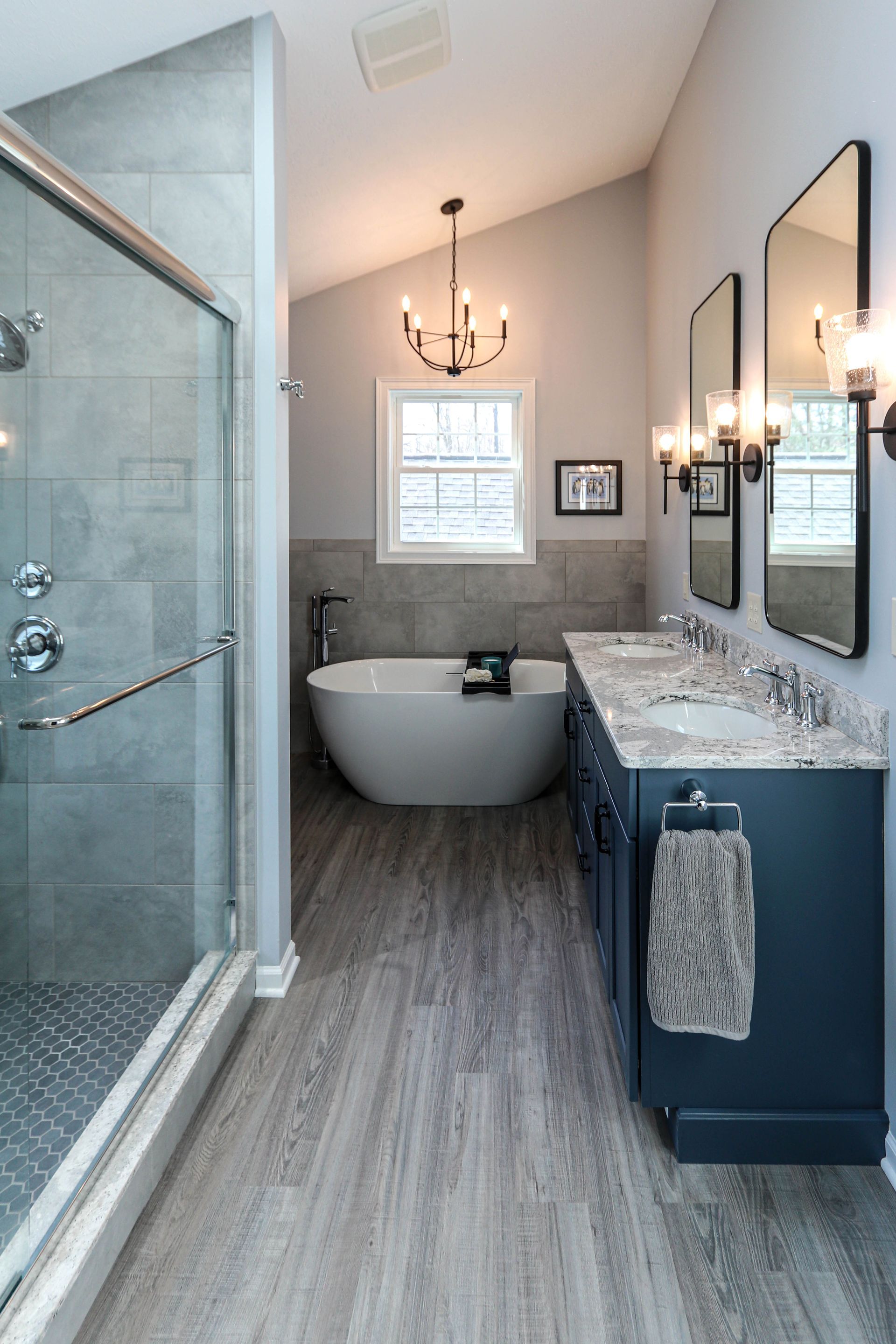 A bathroom with a tub , sinks , and a walk in shower.