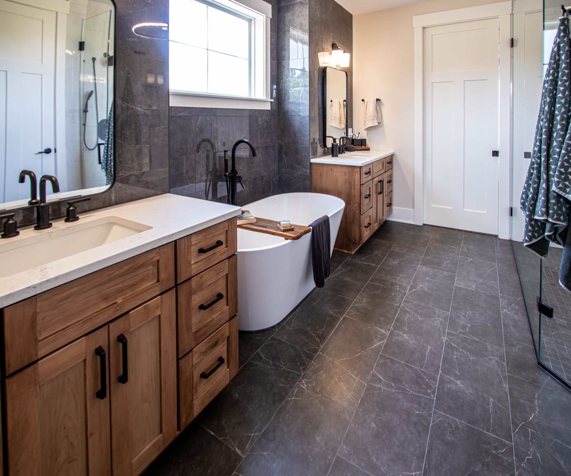 A bathroom with two sinks , a tub , and a window.