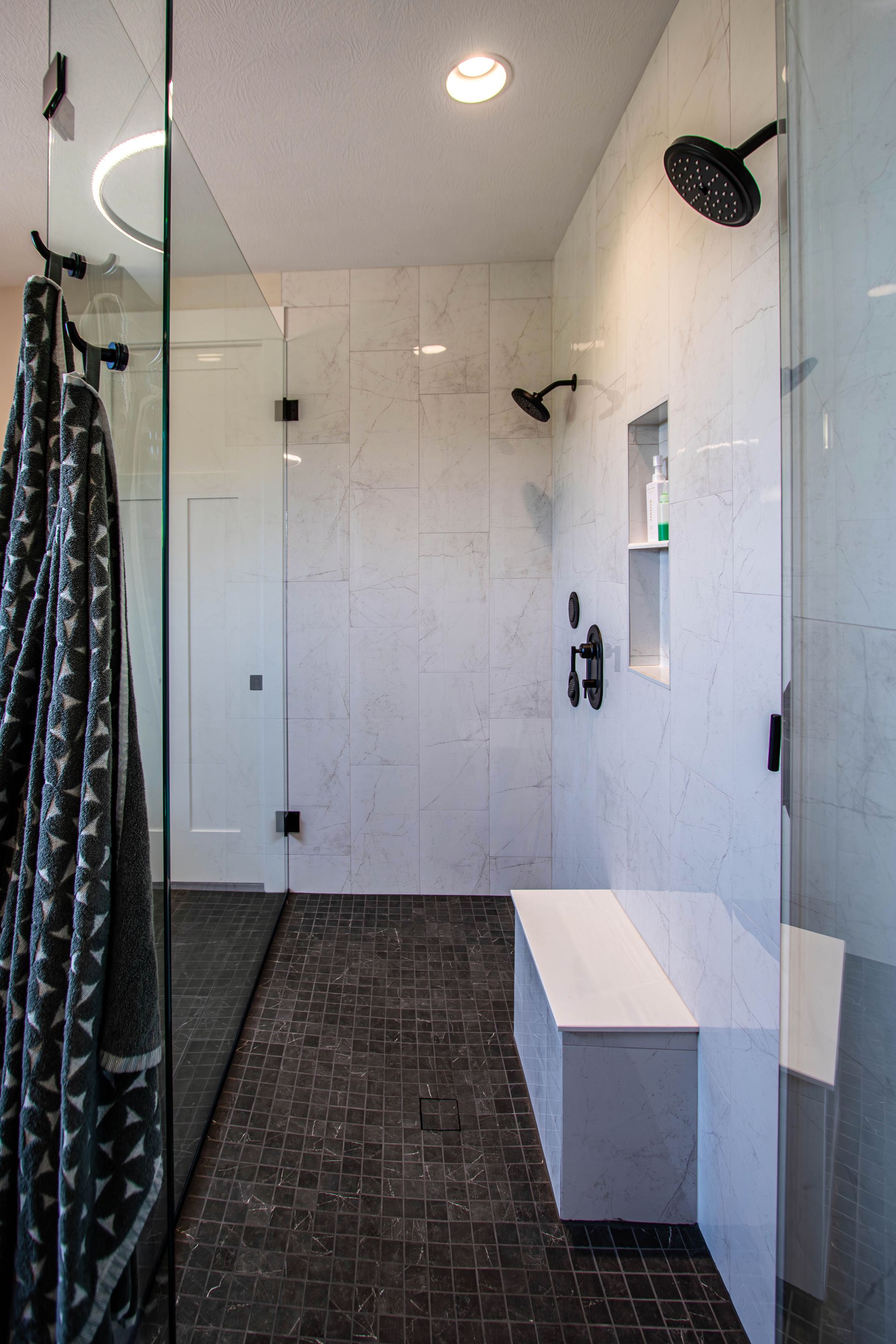 A bathroom with a walk in shower and a bench.