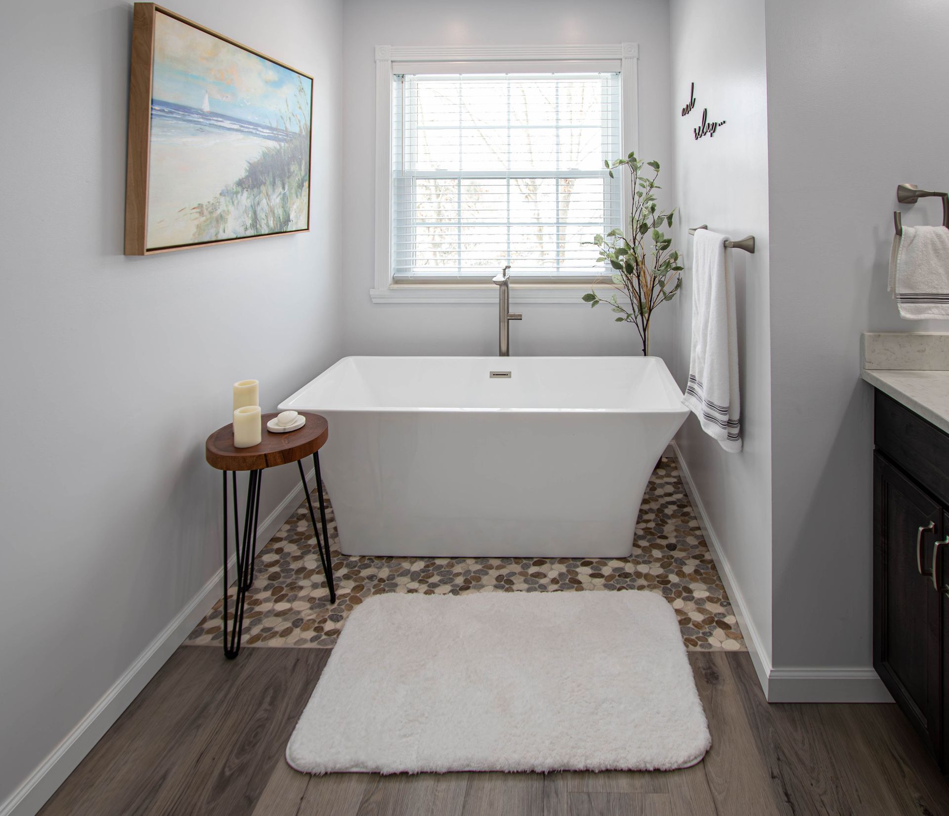 A bathroom with a bathtub and a rug on the floor.