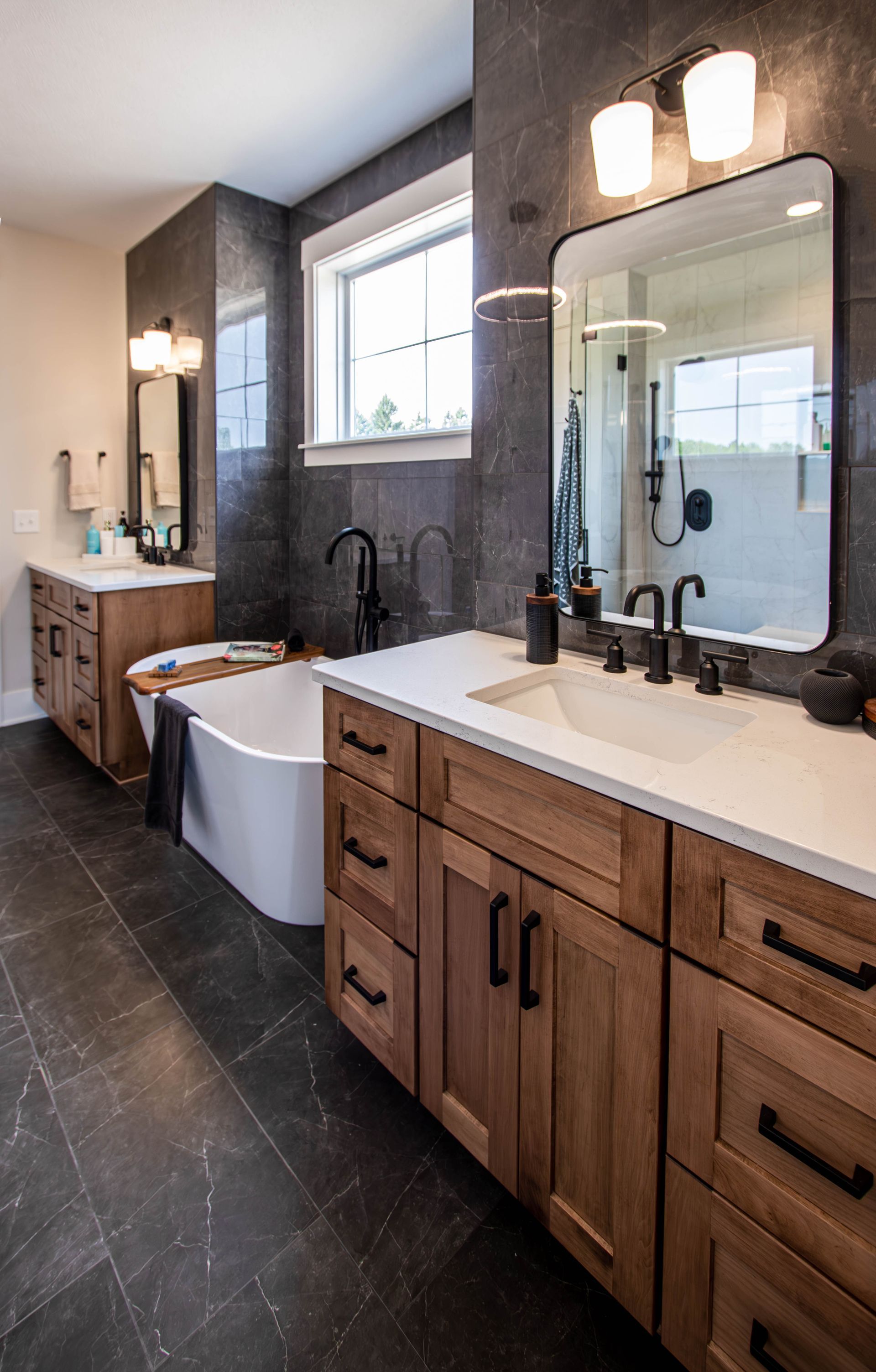 A bathroom with two sinks , a tub , and a large mirror.