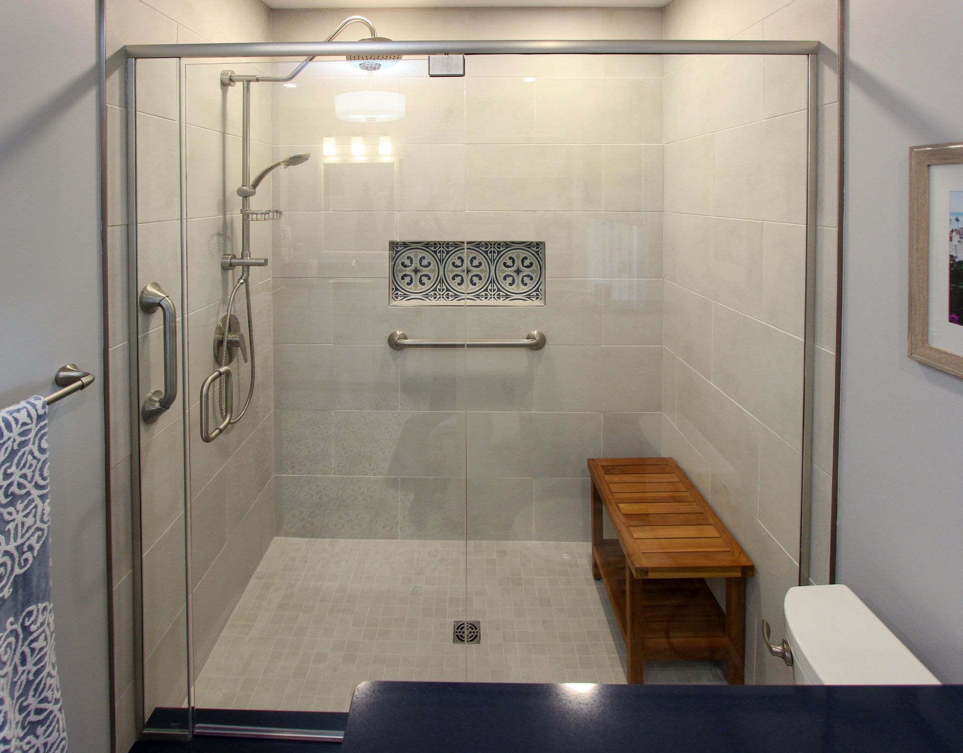 A bathroom with a walk in shower and a wooden bench