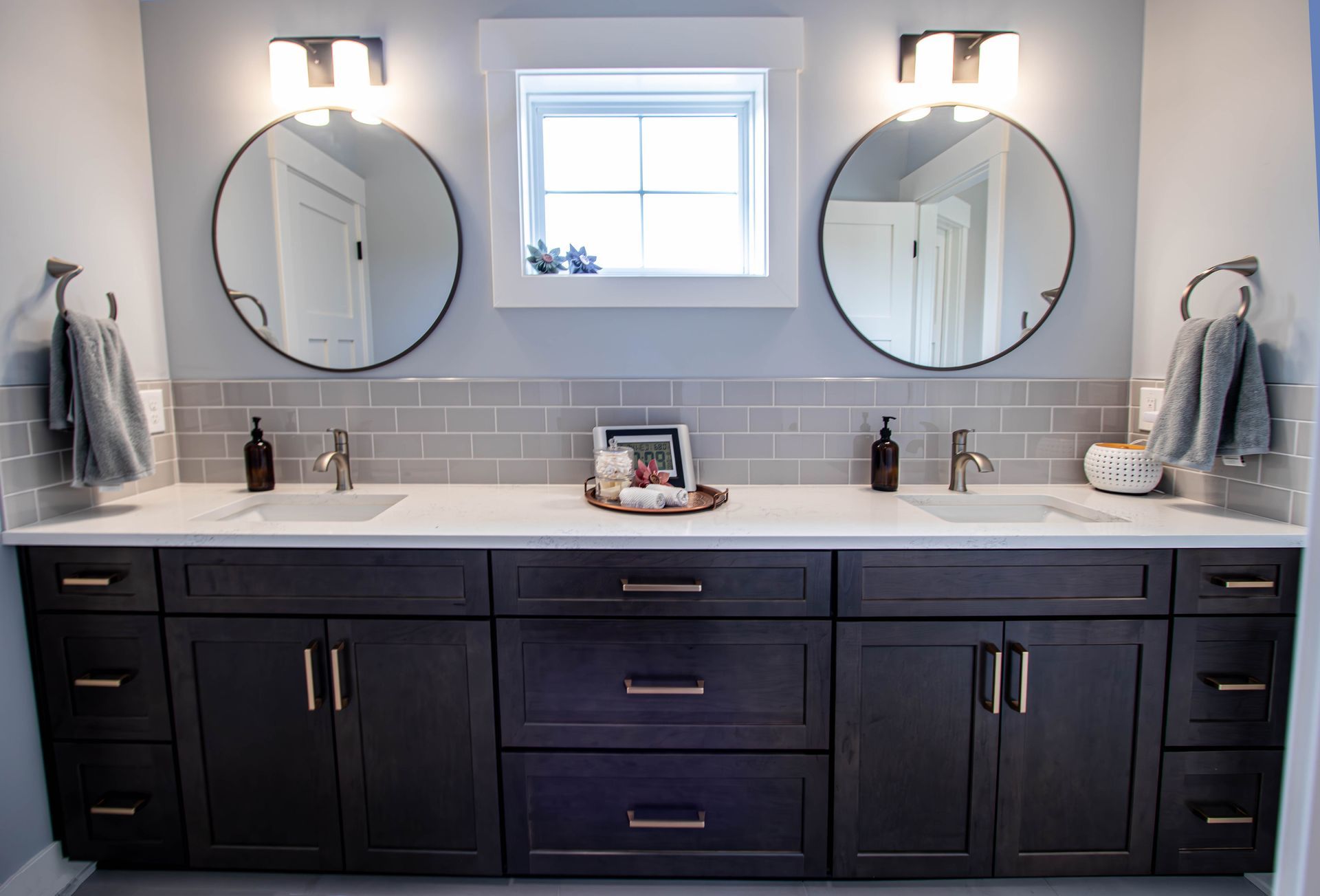 A bathroom with two sinks and two round mirrors.