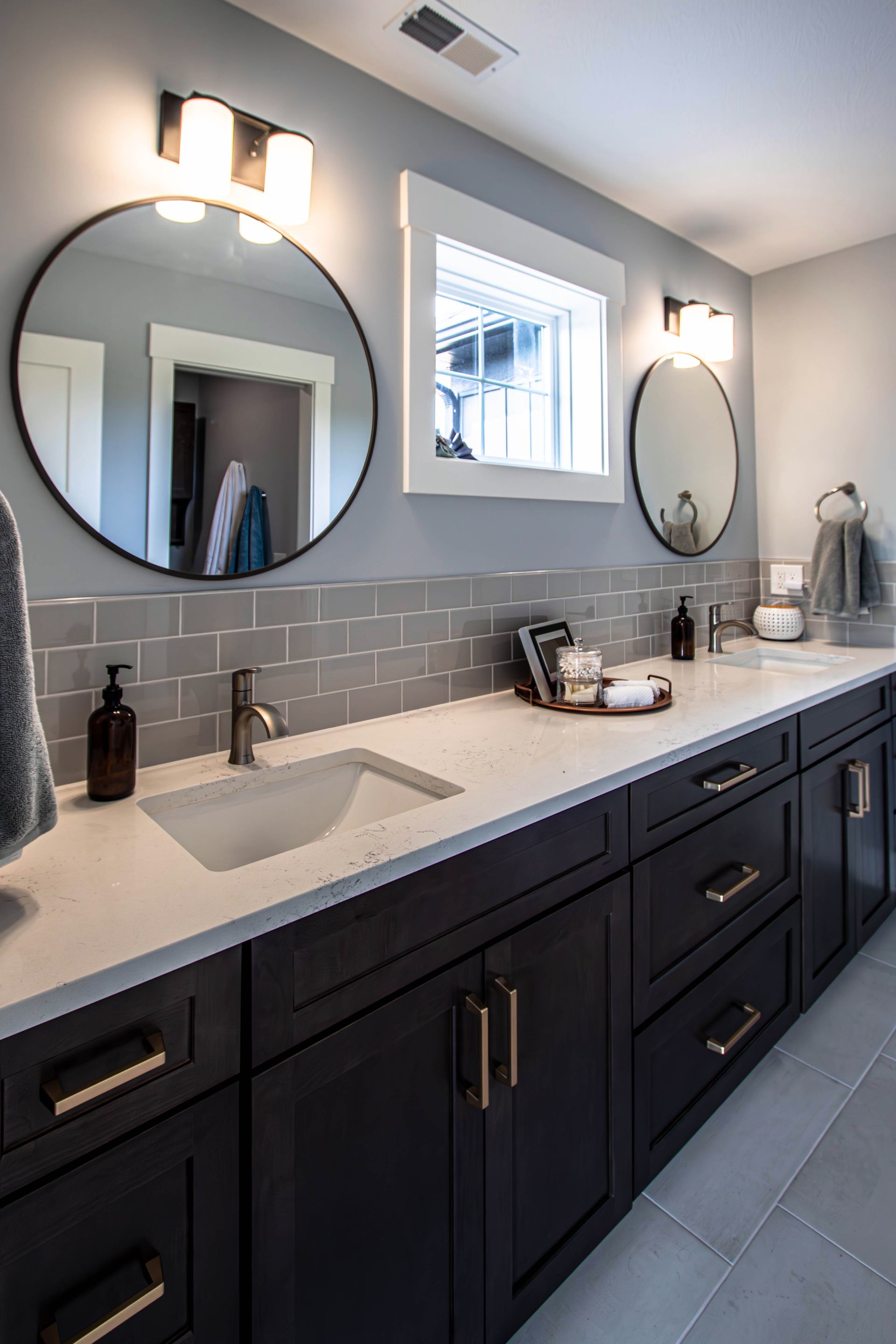 A bathroom with two sinks , two mirrors and a window.
