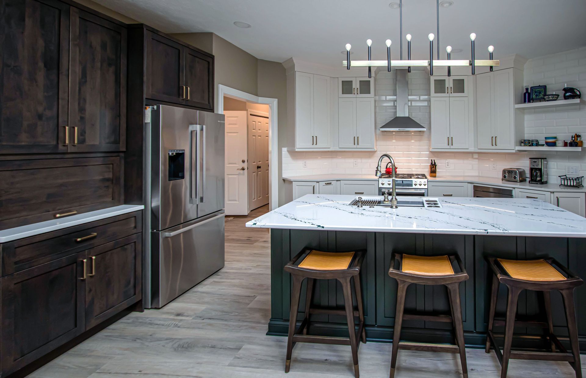 A kitchen with stools and a large island in the middle.