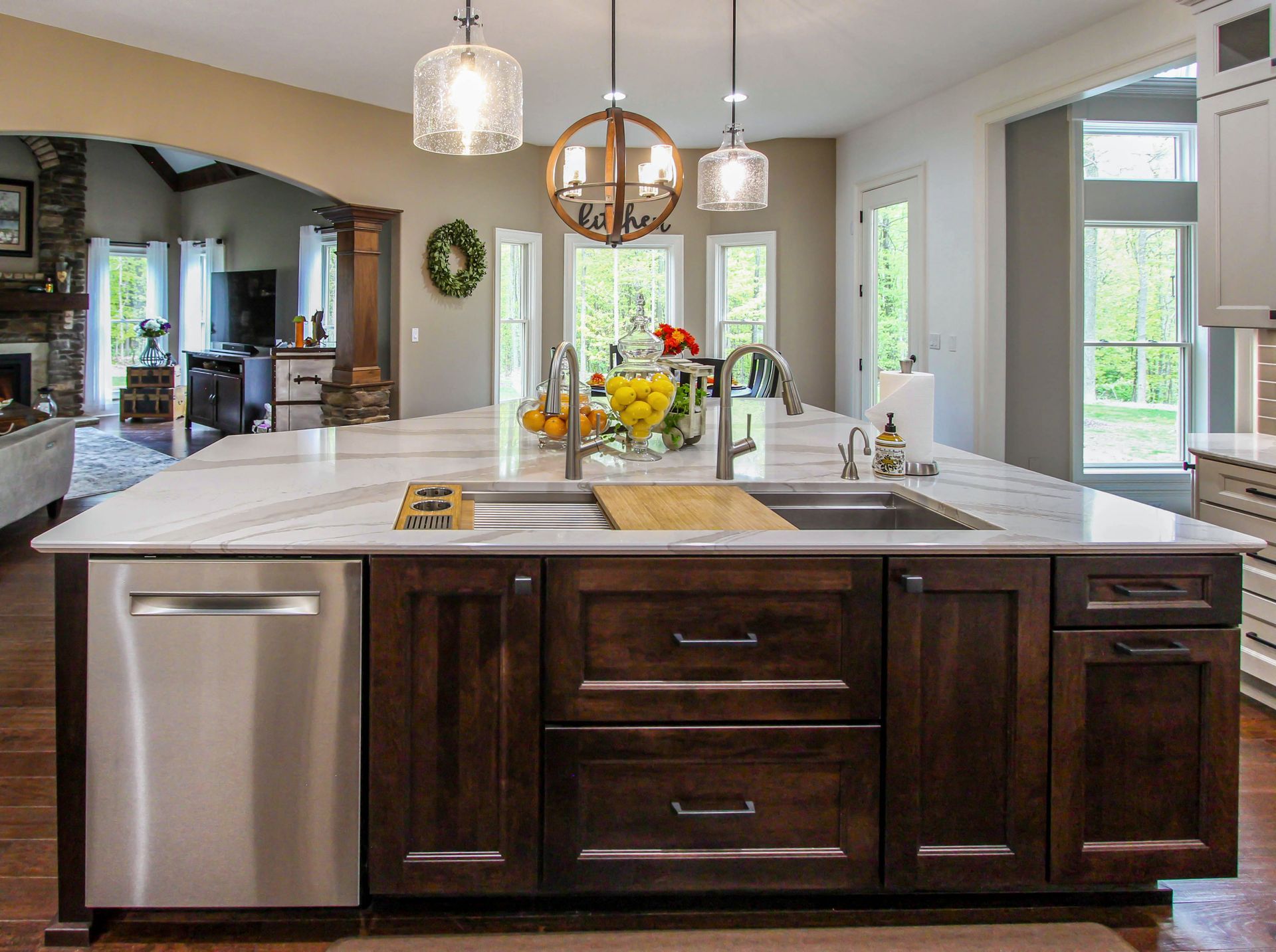 A kitchen with a large island , sink , dishwasher and stainless steel appliances.