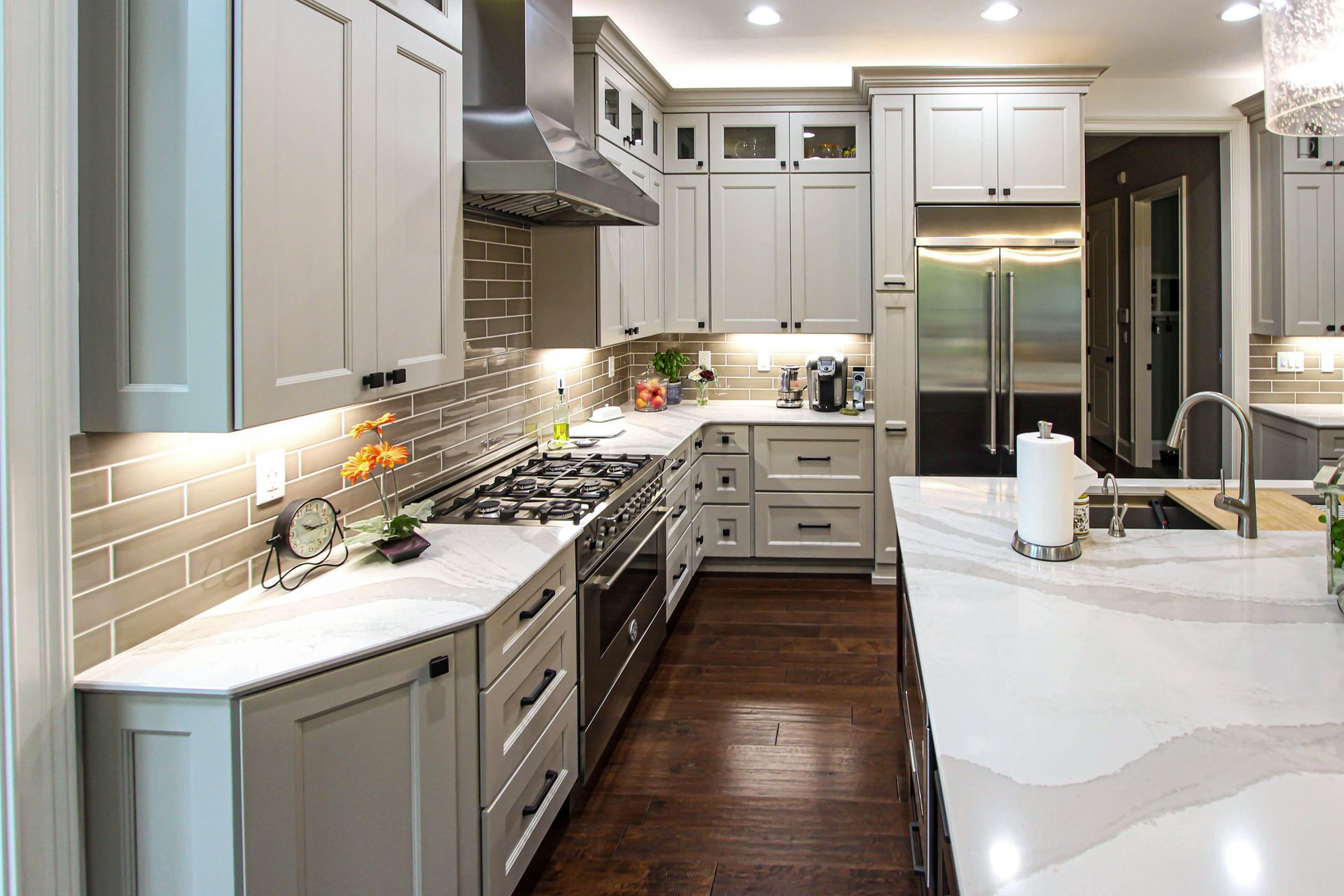A kitchen with white cabinets, stainless steel appliances, and a large island.