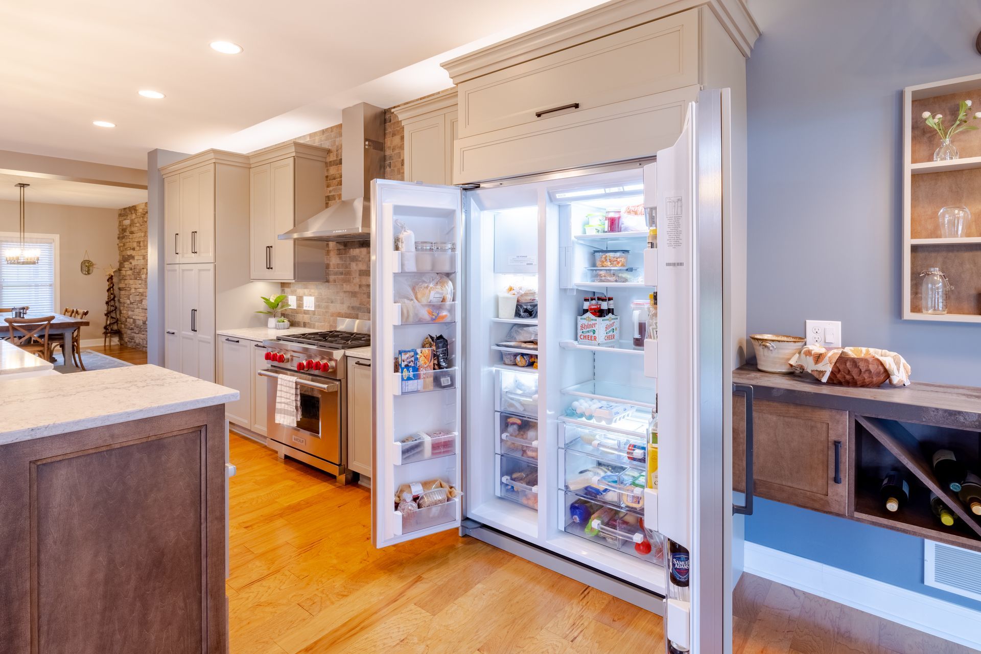 A kitchen with a refrigerator that is open and filled with food.