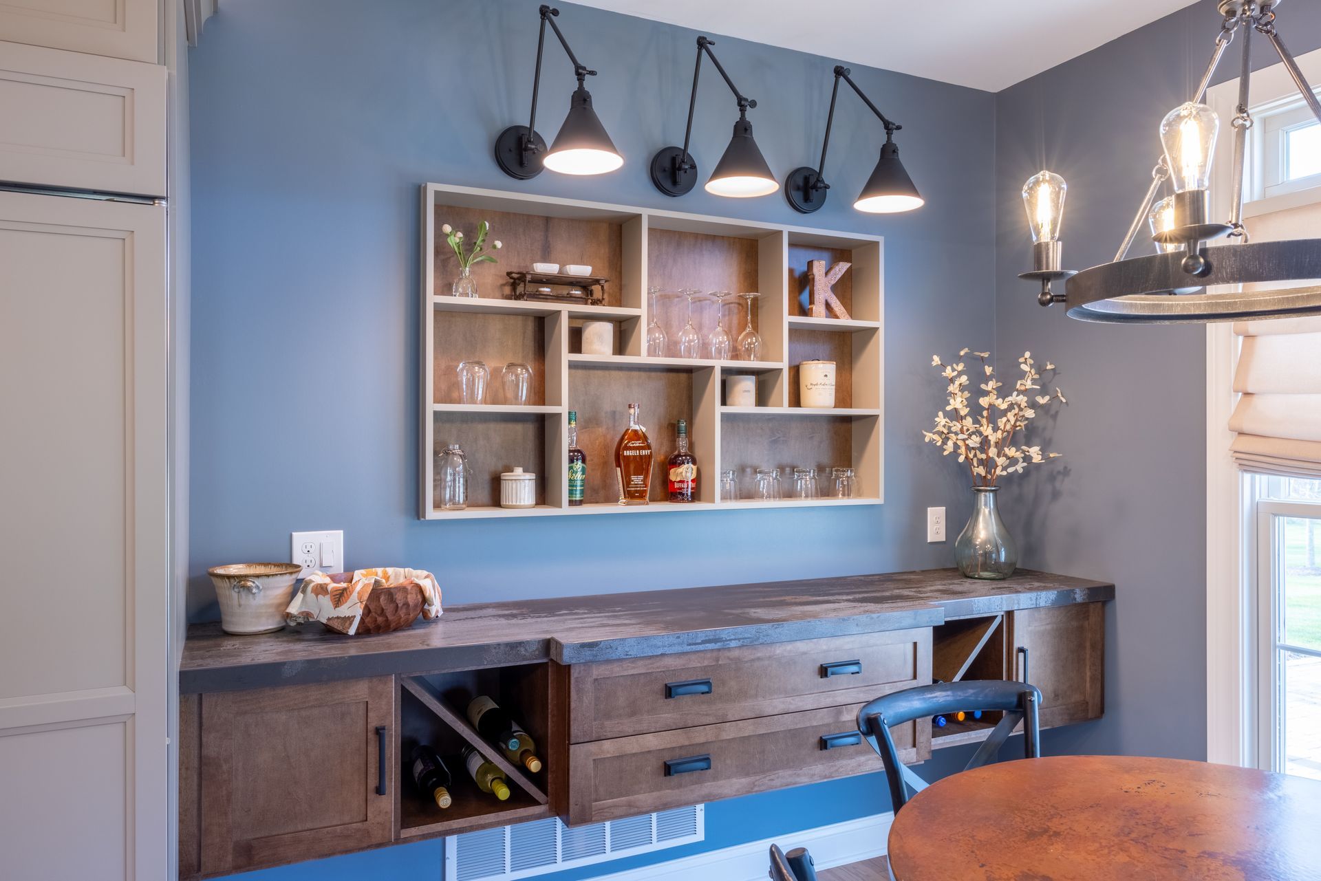 A dining room with a table , chairs , shelves and a wine rack.