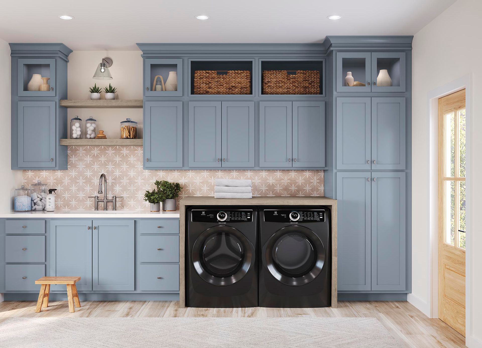 A laundry room with blue cabinets and black washer and dryer