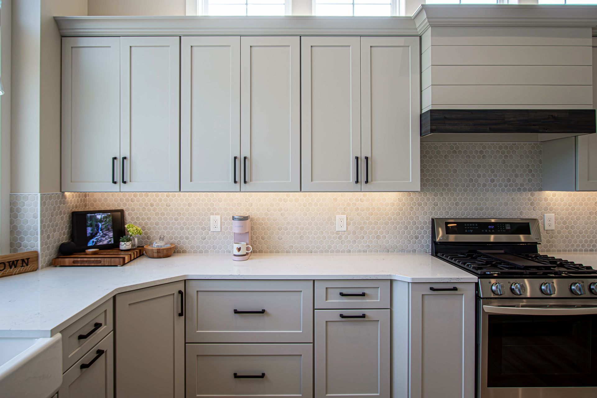 A kitchen with white cabinets , a stove , and a sink.