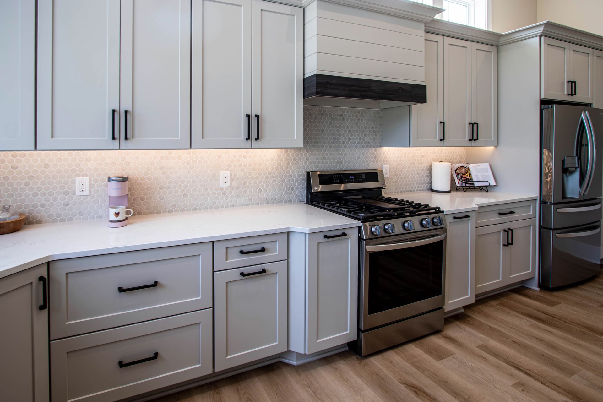 A kitchen with white cabinets , stainless steel appliances , and a refrigerator.