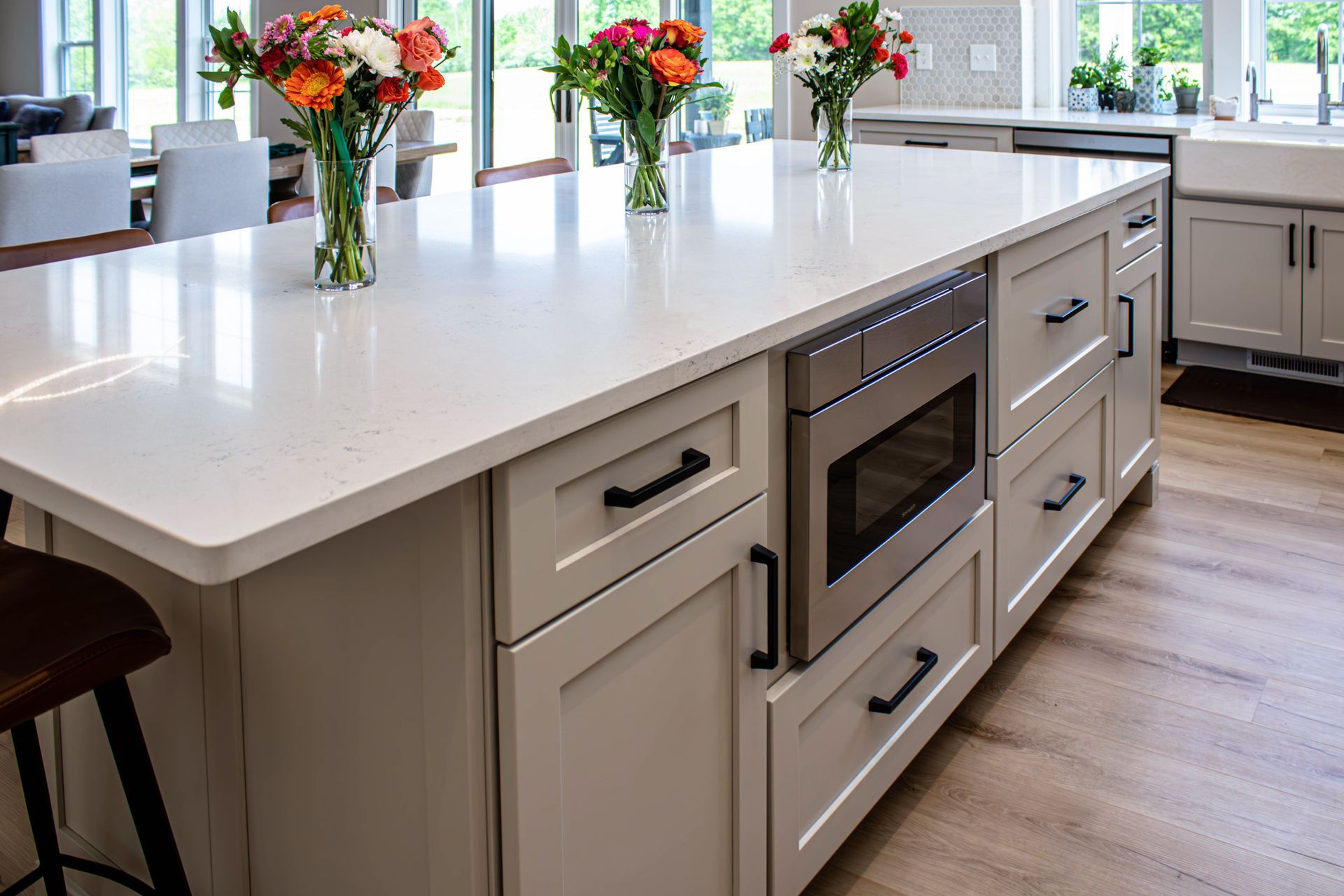 A kitchen with white cabinets and a large island with flowers on it.