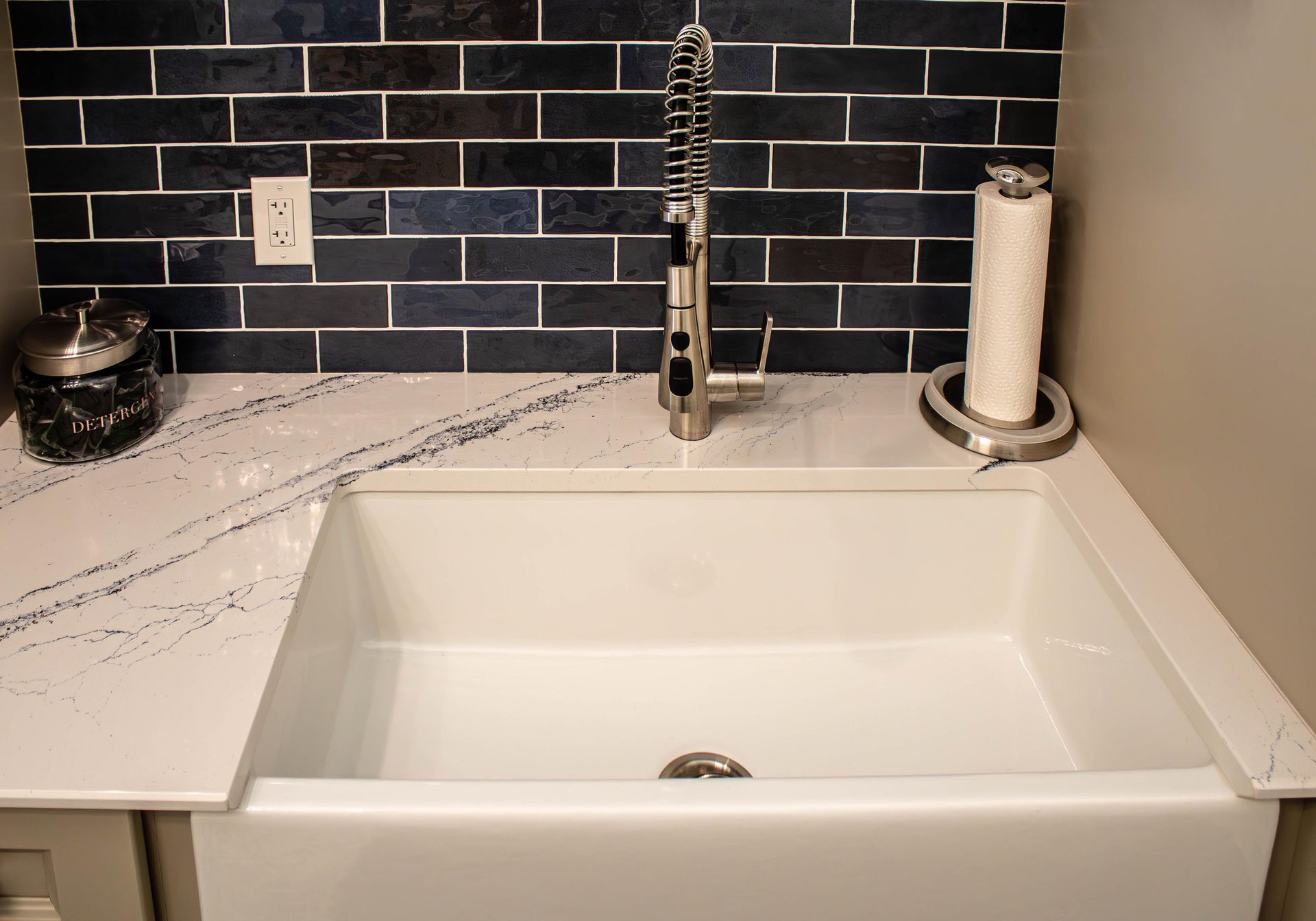 A kitchen sink with a faucet and a paper towel holder.