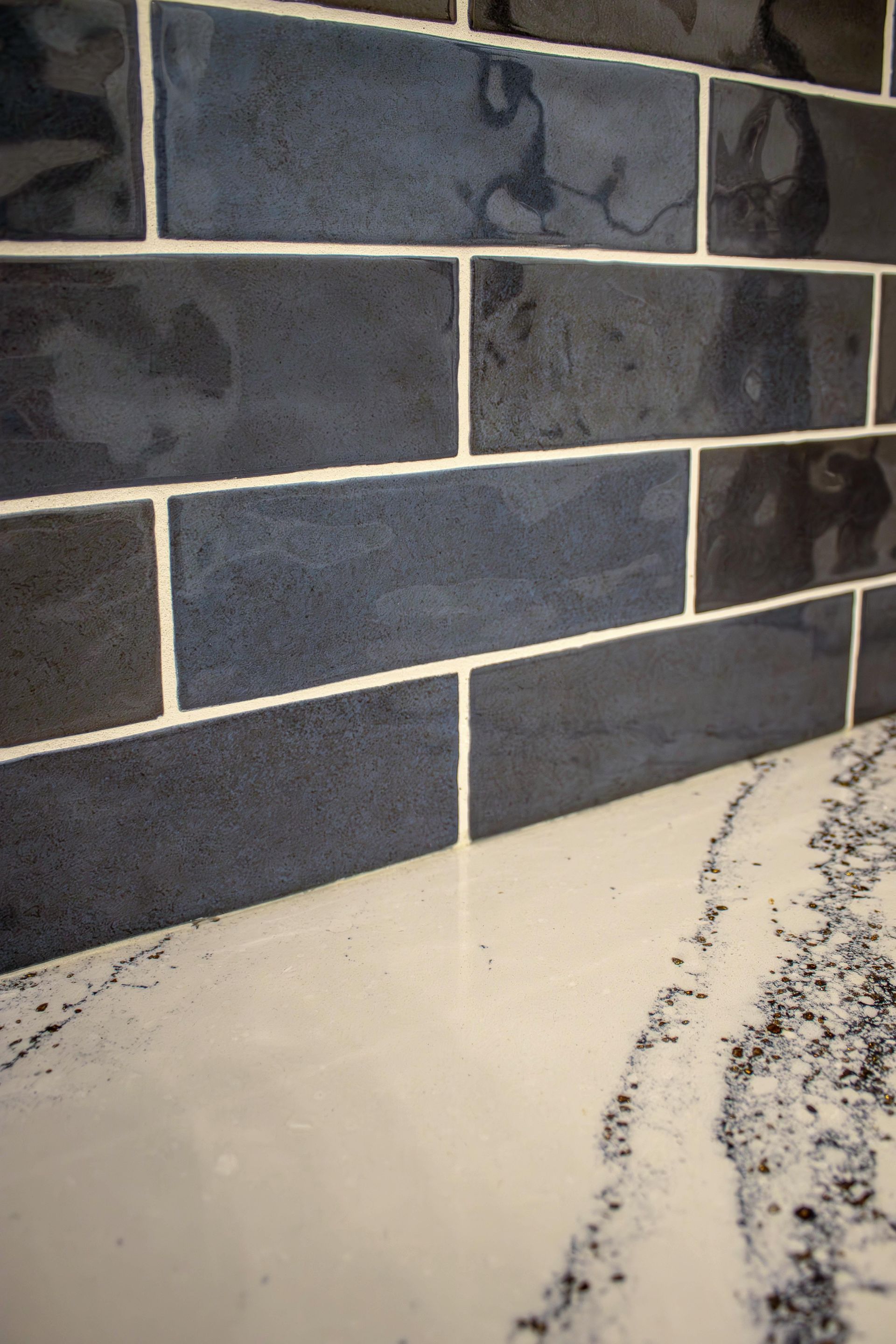 A close up of a blue tile wall next to a white counter top.