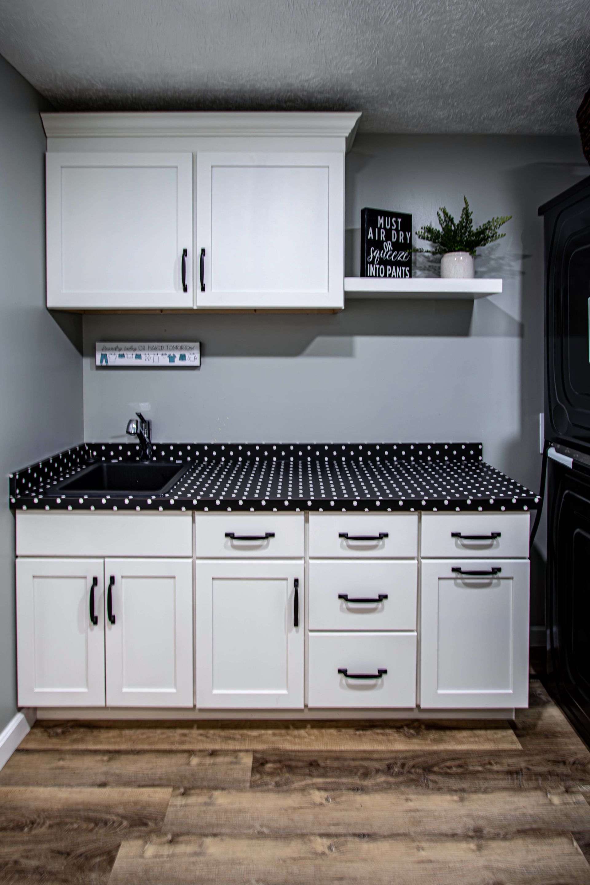 A kitchen with white cabinets and black counter tops