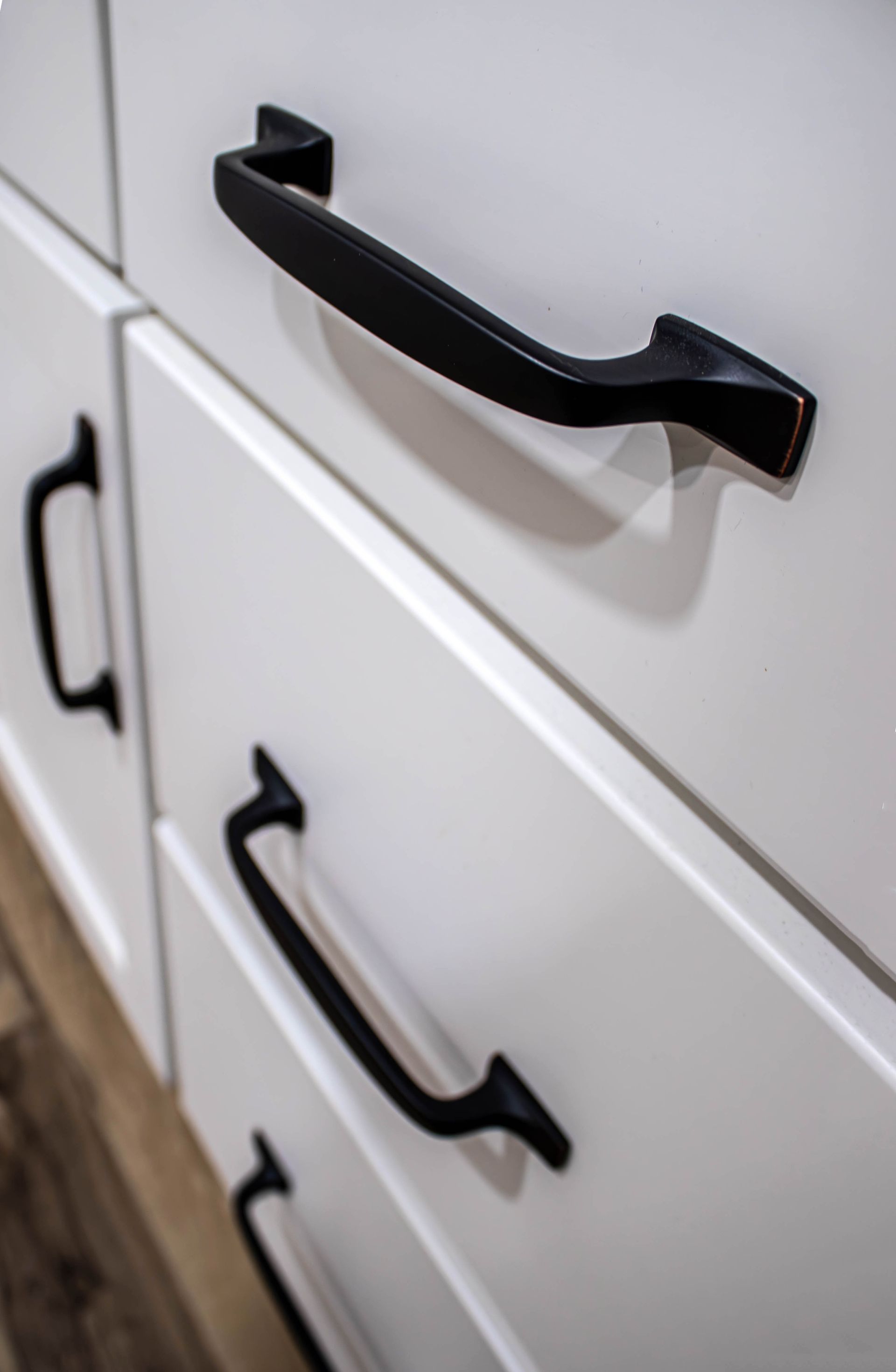 A close up of a white cabinet with black handles.