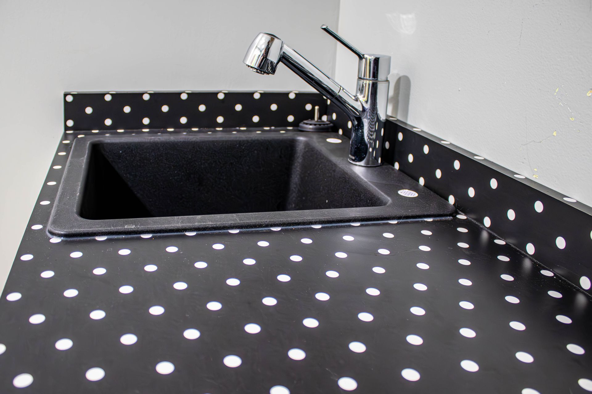 A black sink with white polka dots on the counter top