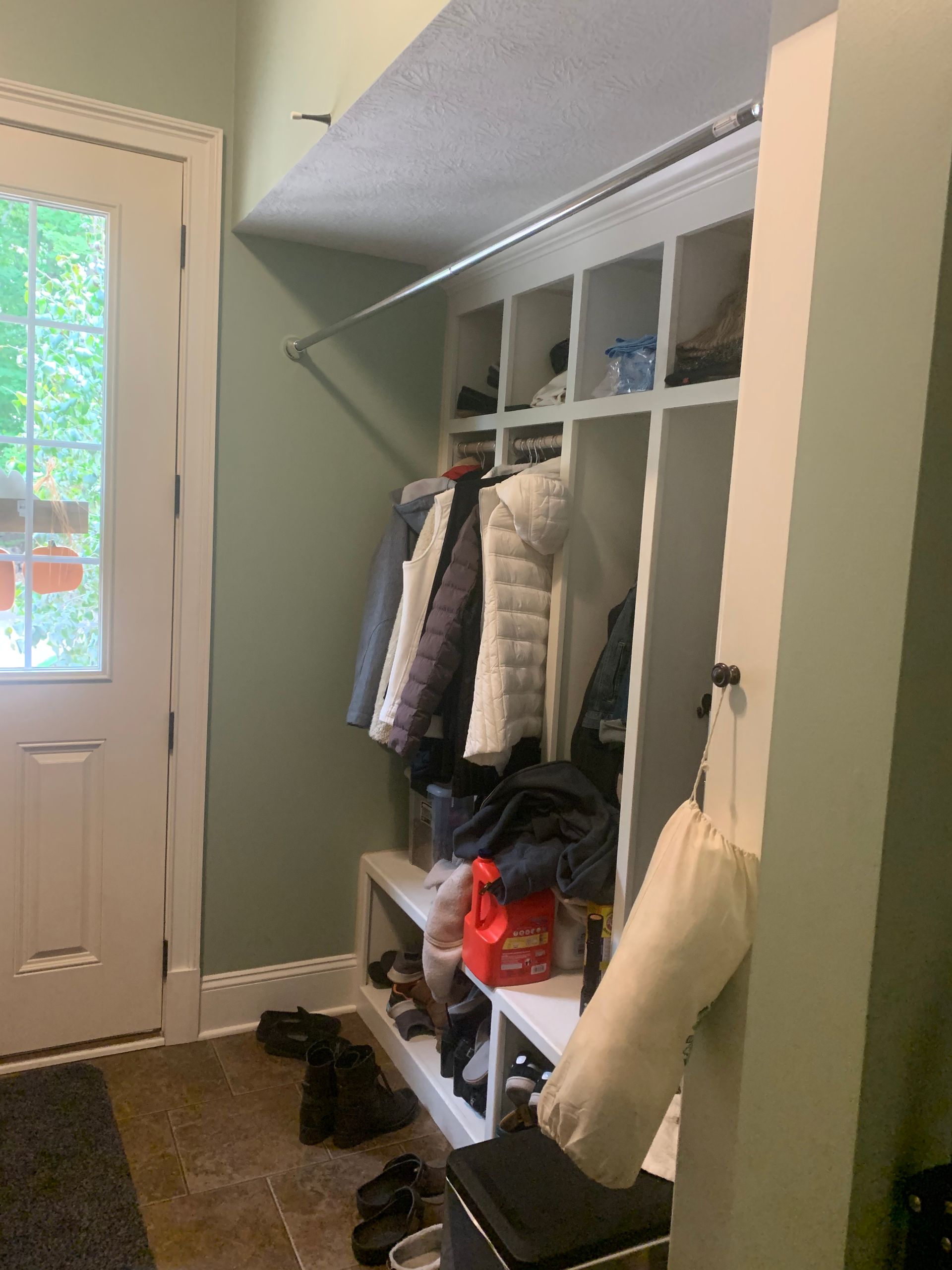 A mud room with clothes hanging on racks and shoes on a bench.