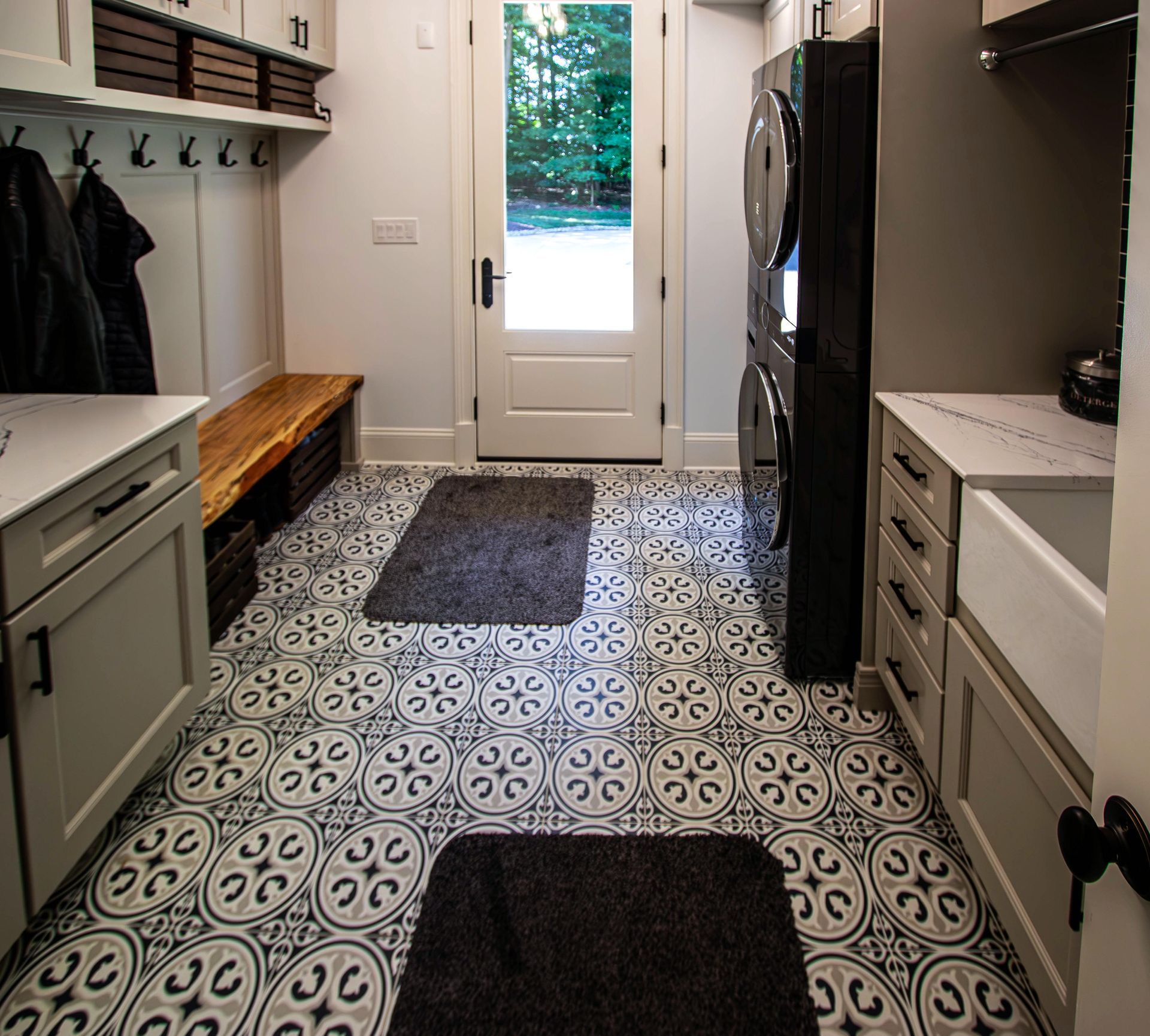 A laundry room with a black rug on the floor