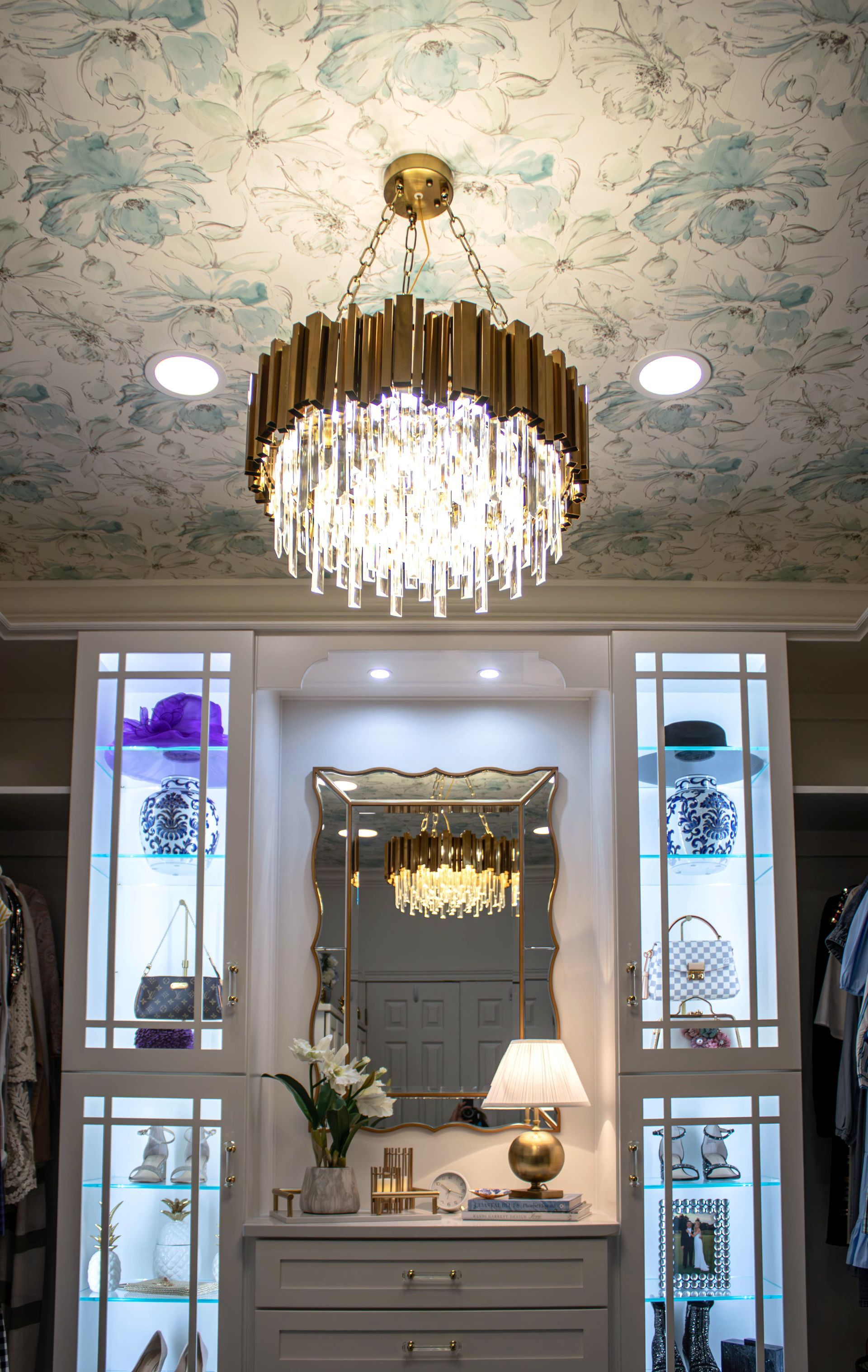 A closet with a chandelier hanging from the ceiling and a mirror.