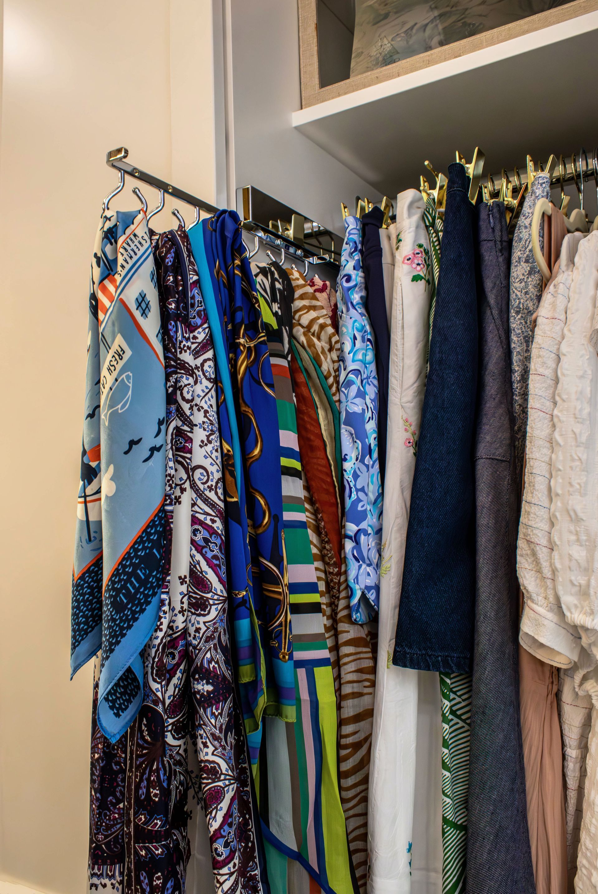 A closet filled with clothes and scarves hanging on racks.