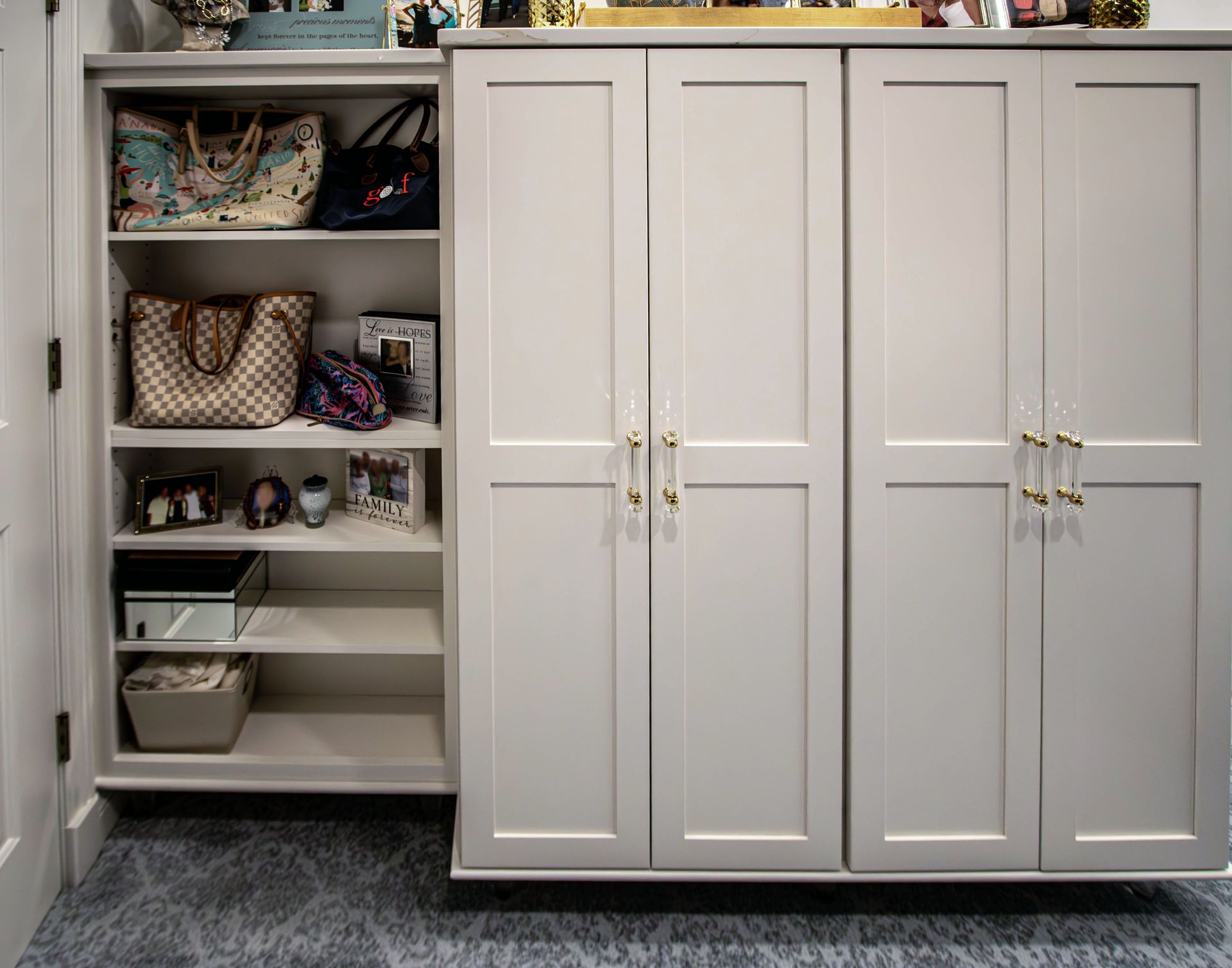 A closet with white cabinets and shelves filled with handbags and other items.