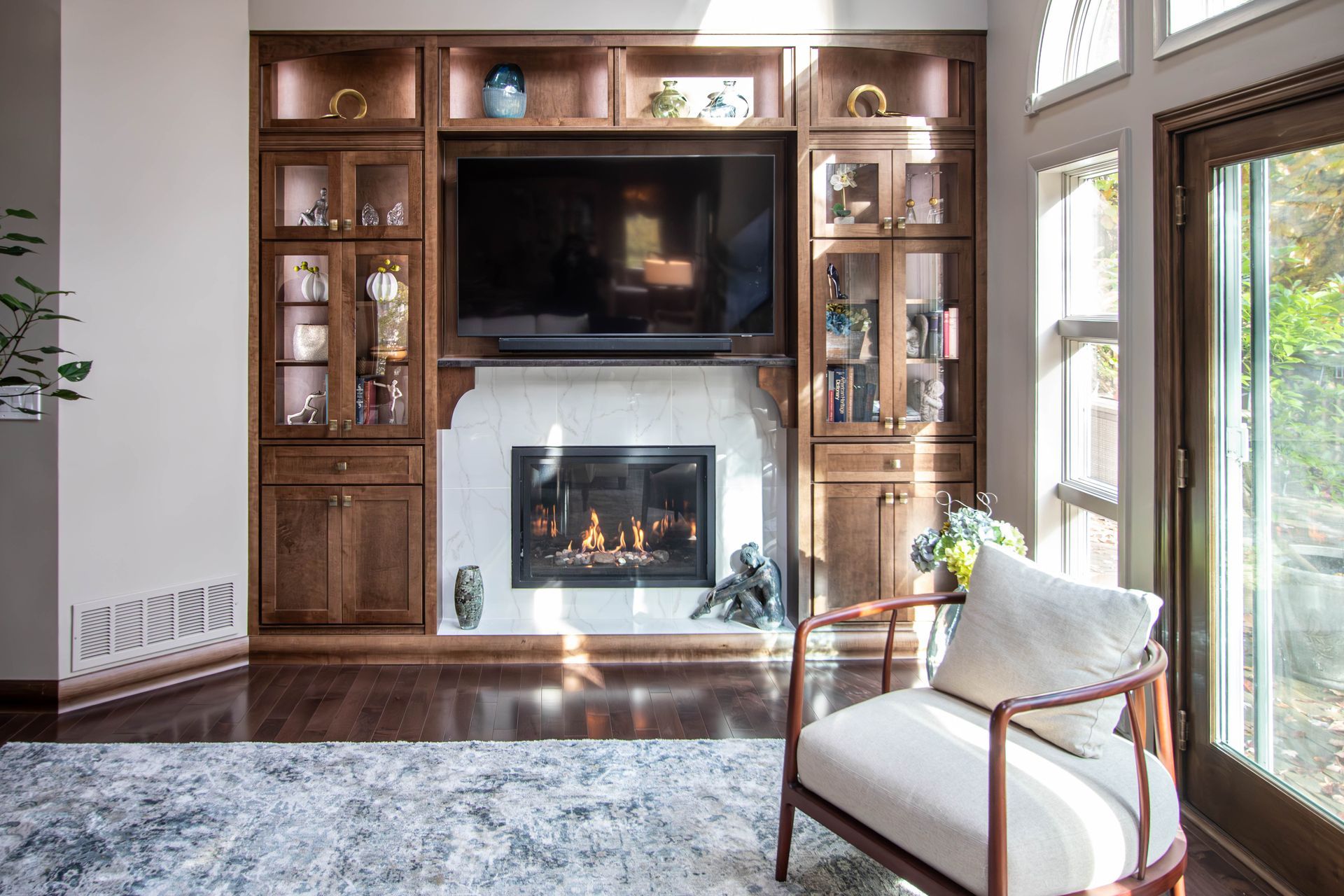 A living room with a fireplace , television , chair and rug.