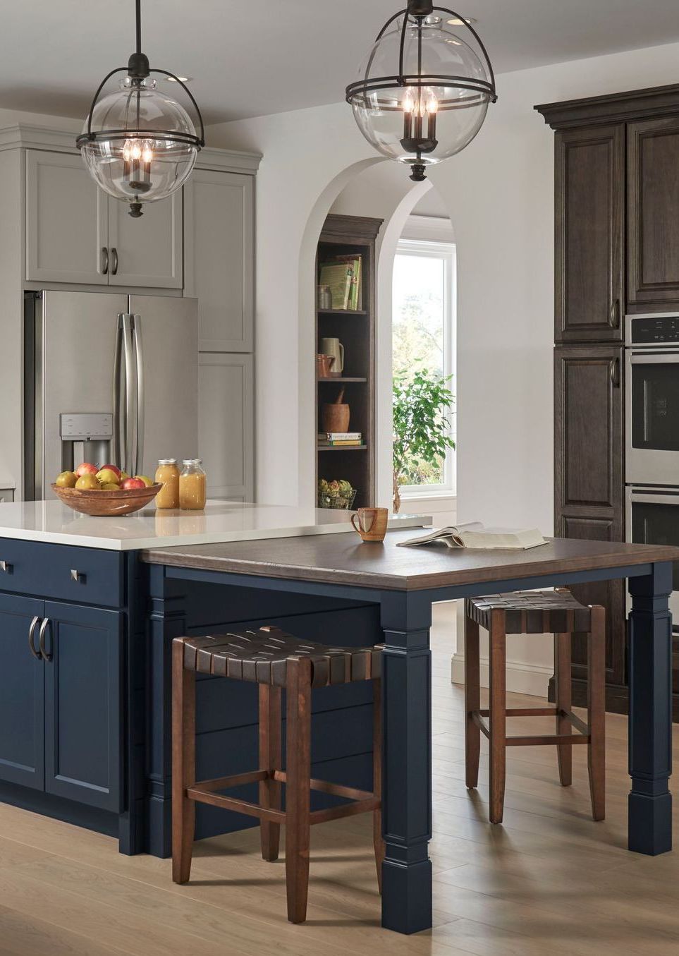 A kitchen with a blue island , stools , a table and a refrigerator.